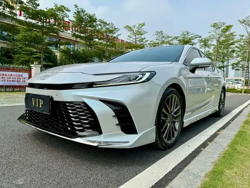 White Toyota Camry viewed from the front quarter on a tree-lined road